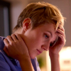 A tired-looking nurse, with her hand on her forehead. 
