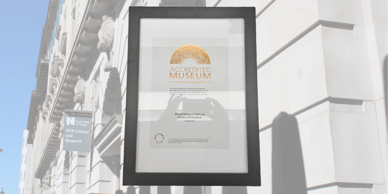 Framed, A4 certificate for an 'Accredited Museum', displayed on a partially transparent background image of the RCN building with the grey RCN Library and Museum sign visible.