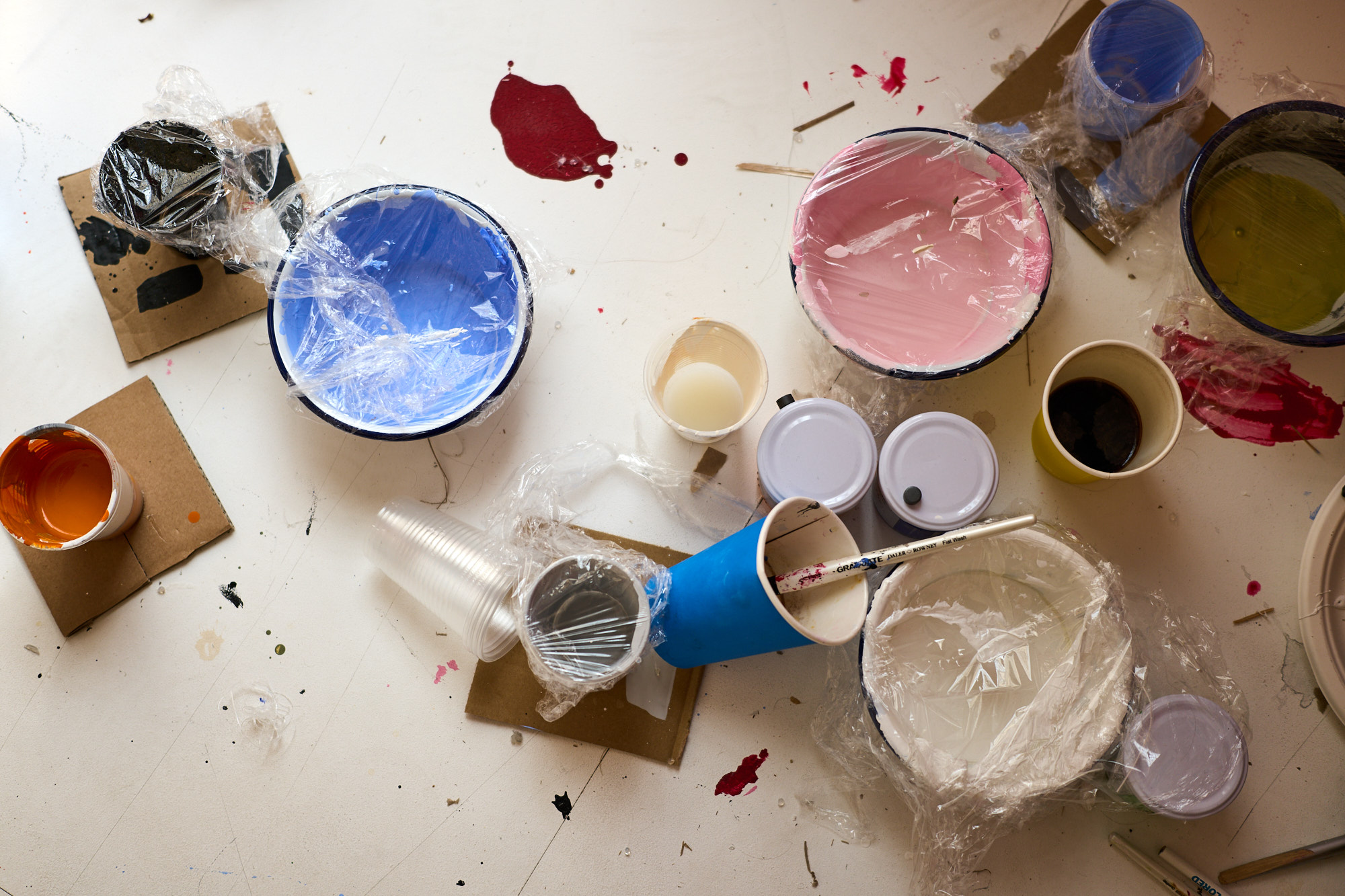 A table with paint pots and paint brushes.