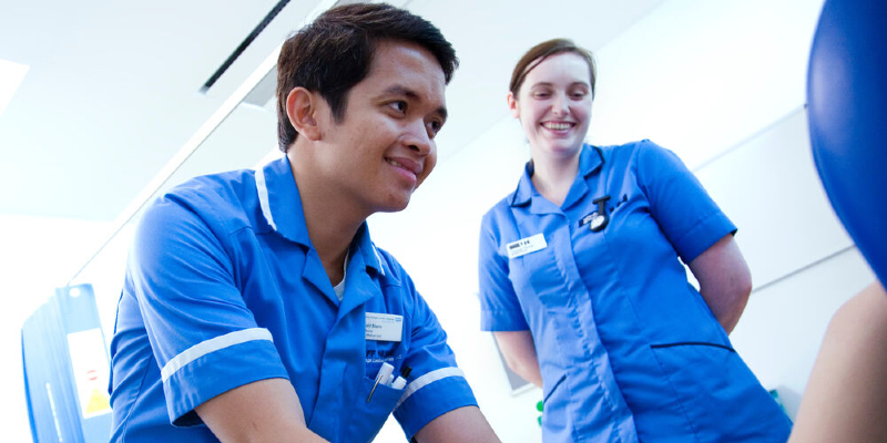 Nursing staff standing at side of bed