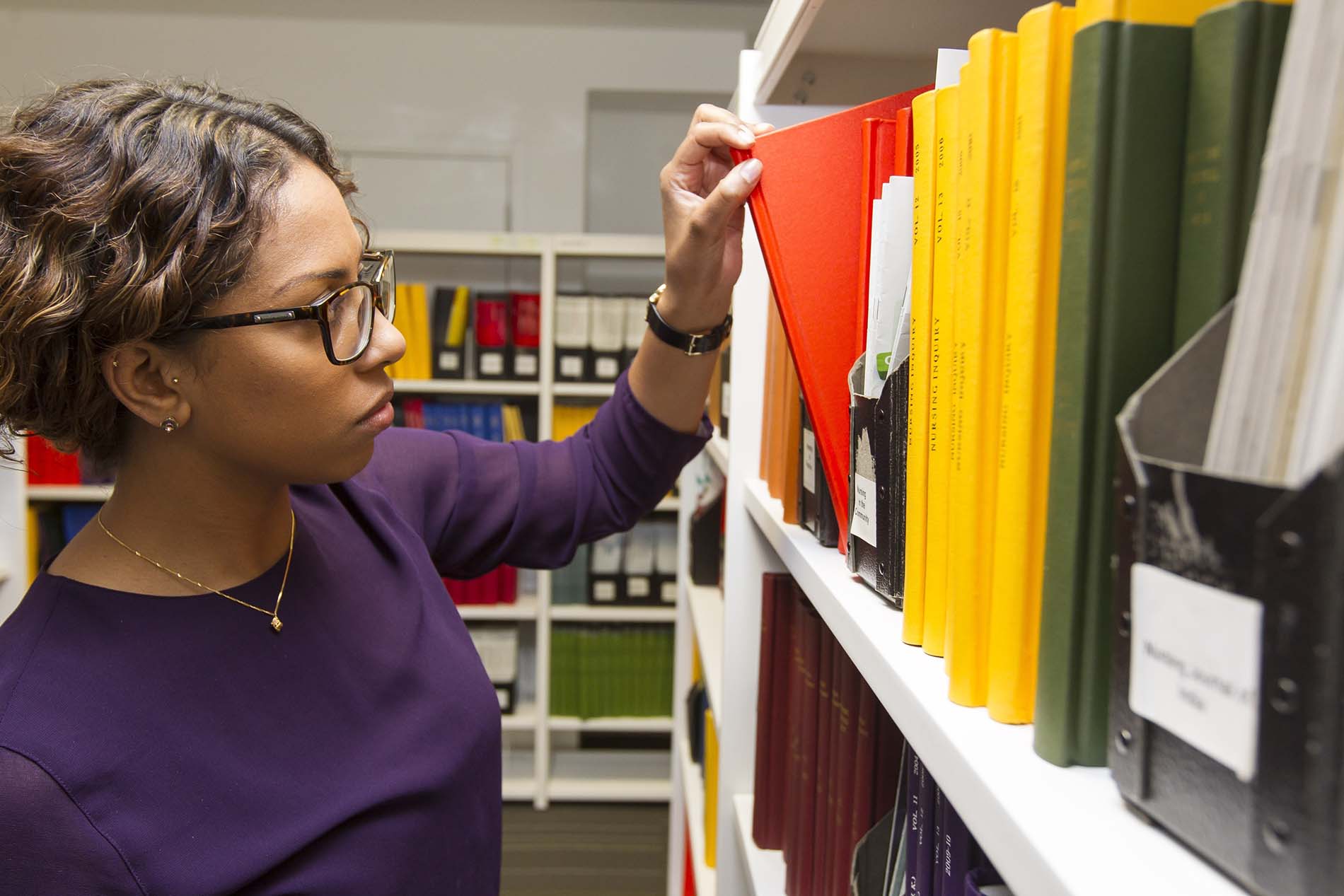 Woman takes file from bookcase