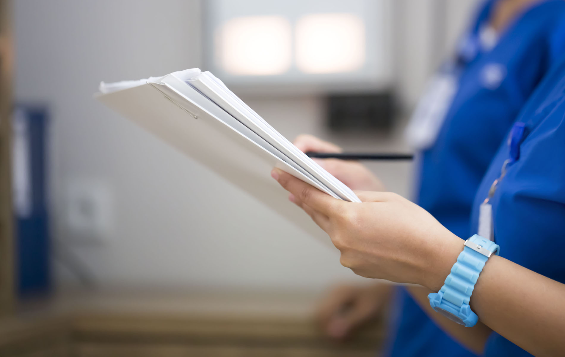 Nurse holds a pile of paper and a pen to make notes