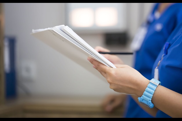 Nurse holds a pile of paper and a pen to make notes