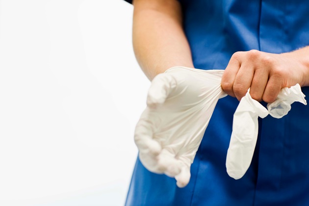 Nurse pulls glove on to hand