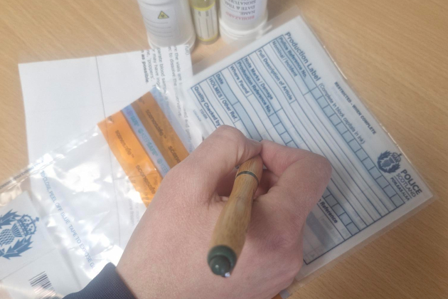 pen held in hand writing label on tamper evident bag