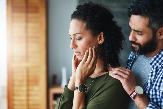 Woman looking upset being comforted by man