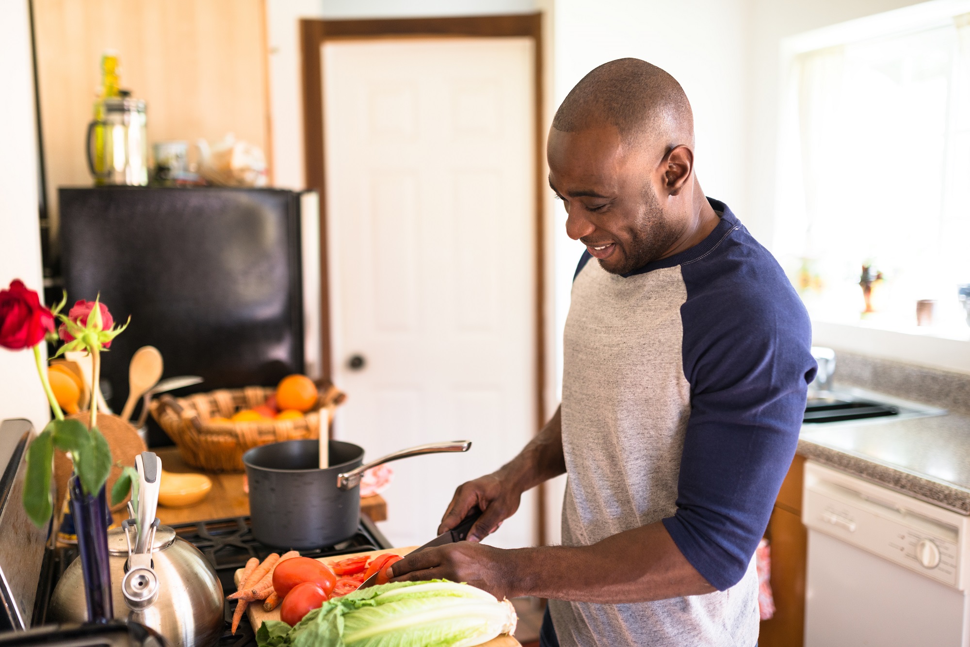 black man cutting up food on a chopping board